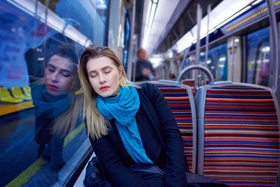 portrait of young woman sleeping inside subway train, feeling exhausted.lifestyle concept.