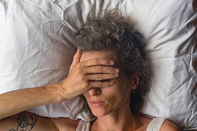 High angle close up  view of middle aged woman sleeping on pillow with hand over eyes (selective focus)