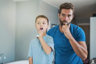 Cropped shot of a handsome young man and his son brushing their teeth in the bathroom