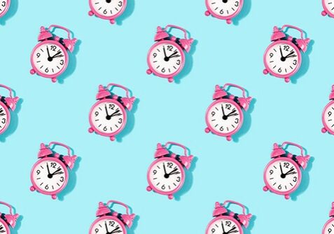 Seamless pattern made with vintage pink alarm clock on turquoise background. Flat lay, top view.