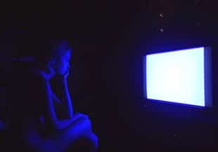 sad caucasian woman watching tv at night