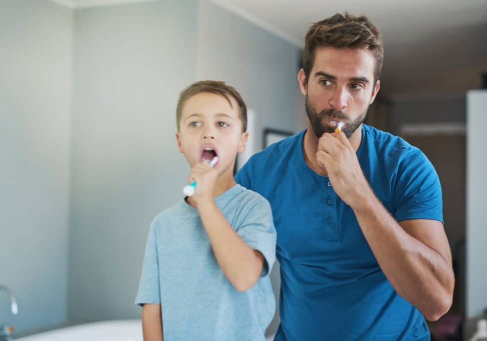 Cropped shot of a handsome young man and his son brushing their teeth in the bathroom